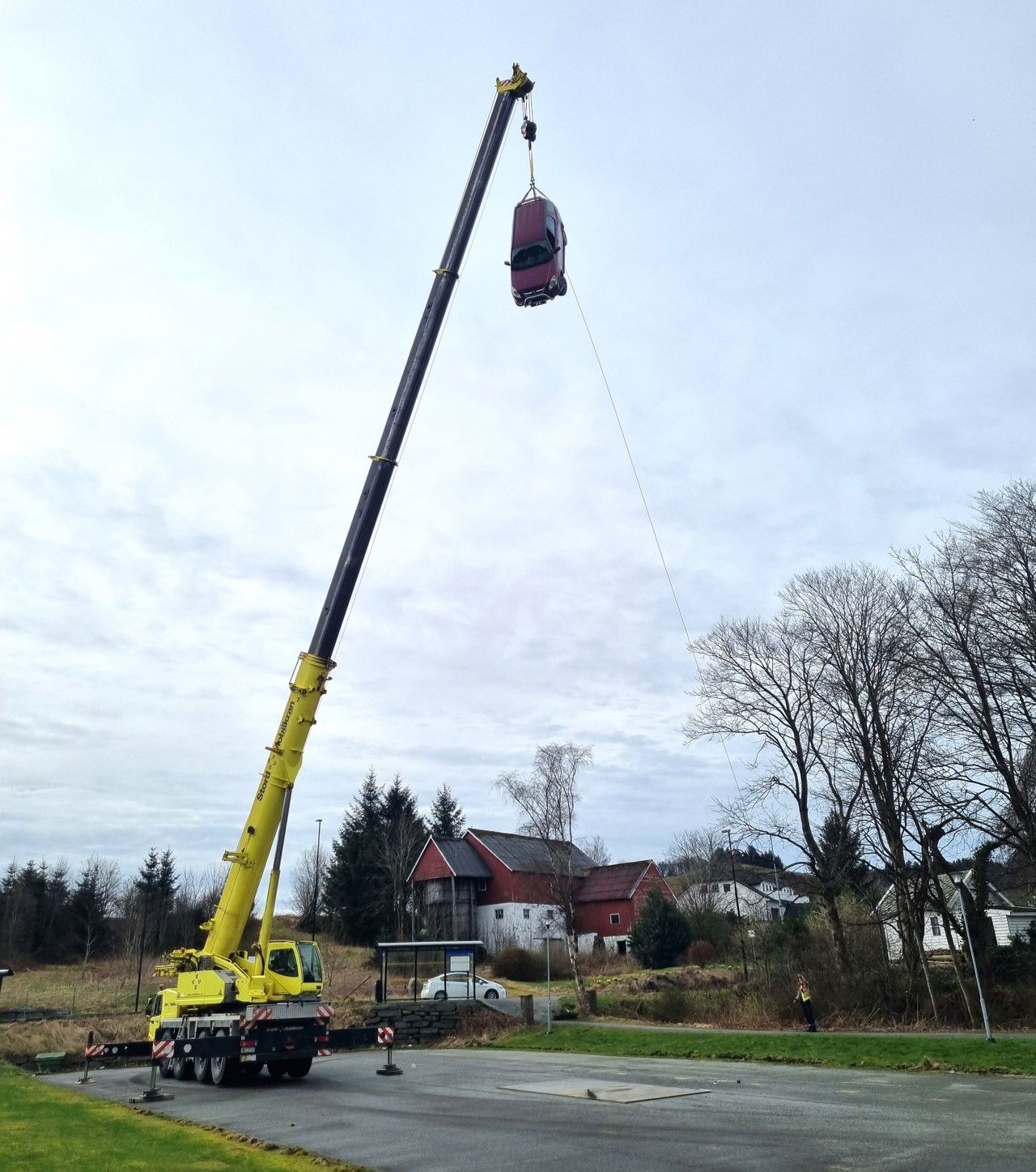 Ein bil er heist opp i toppen av en krane, klar til å sleppast