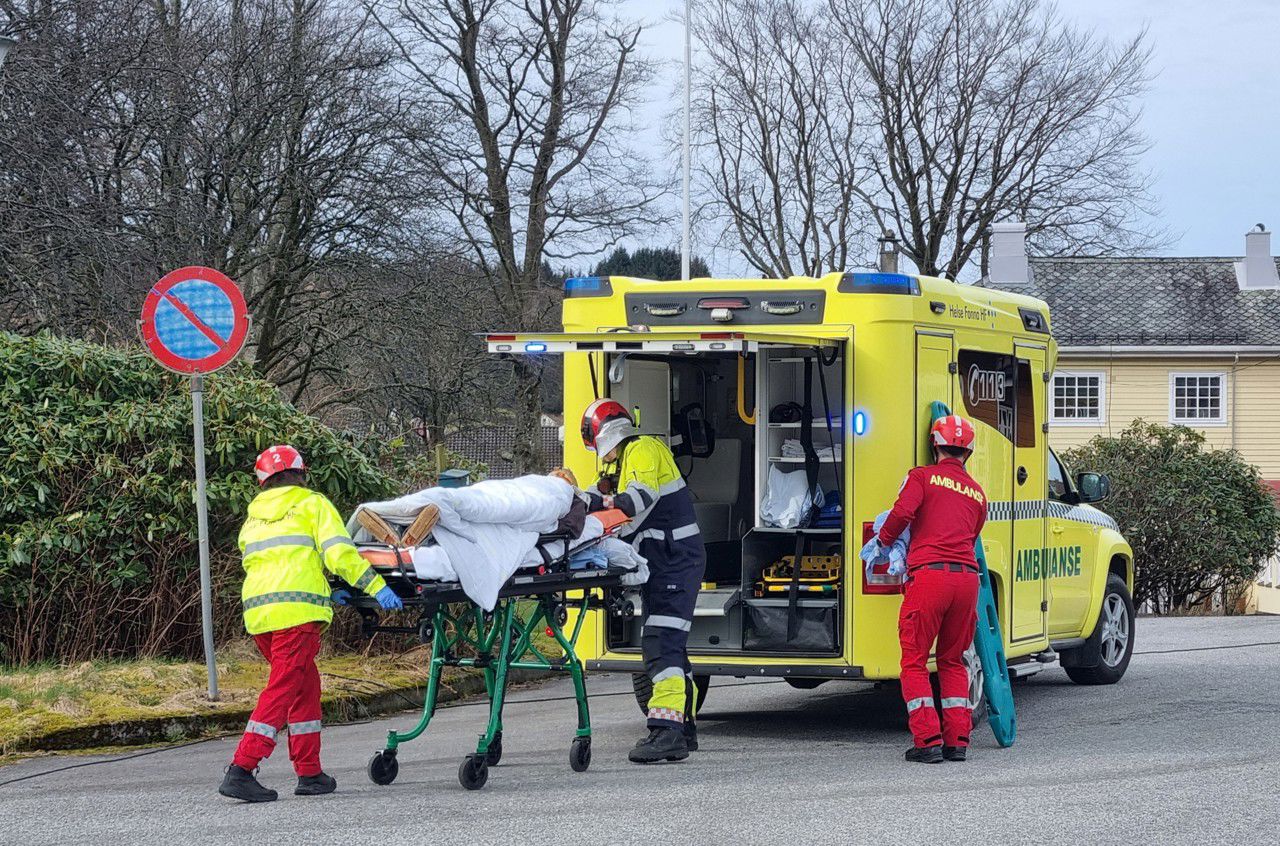 Ei dokke på ei båre blir frakta frå bilvraket og inn i ein ambulanse