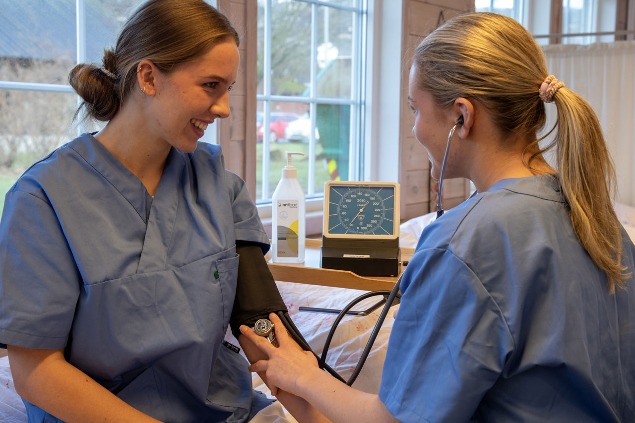 Ein elev og ein lærar måler blodtrykk