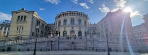Det Norske Storting, sett utanfrå med blå himmel og sol bak