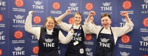 Tre kokkeelevar jublar for sigeren framfor eit banner frå Tine MatCup