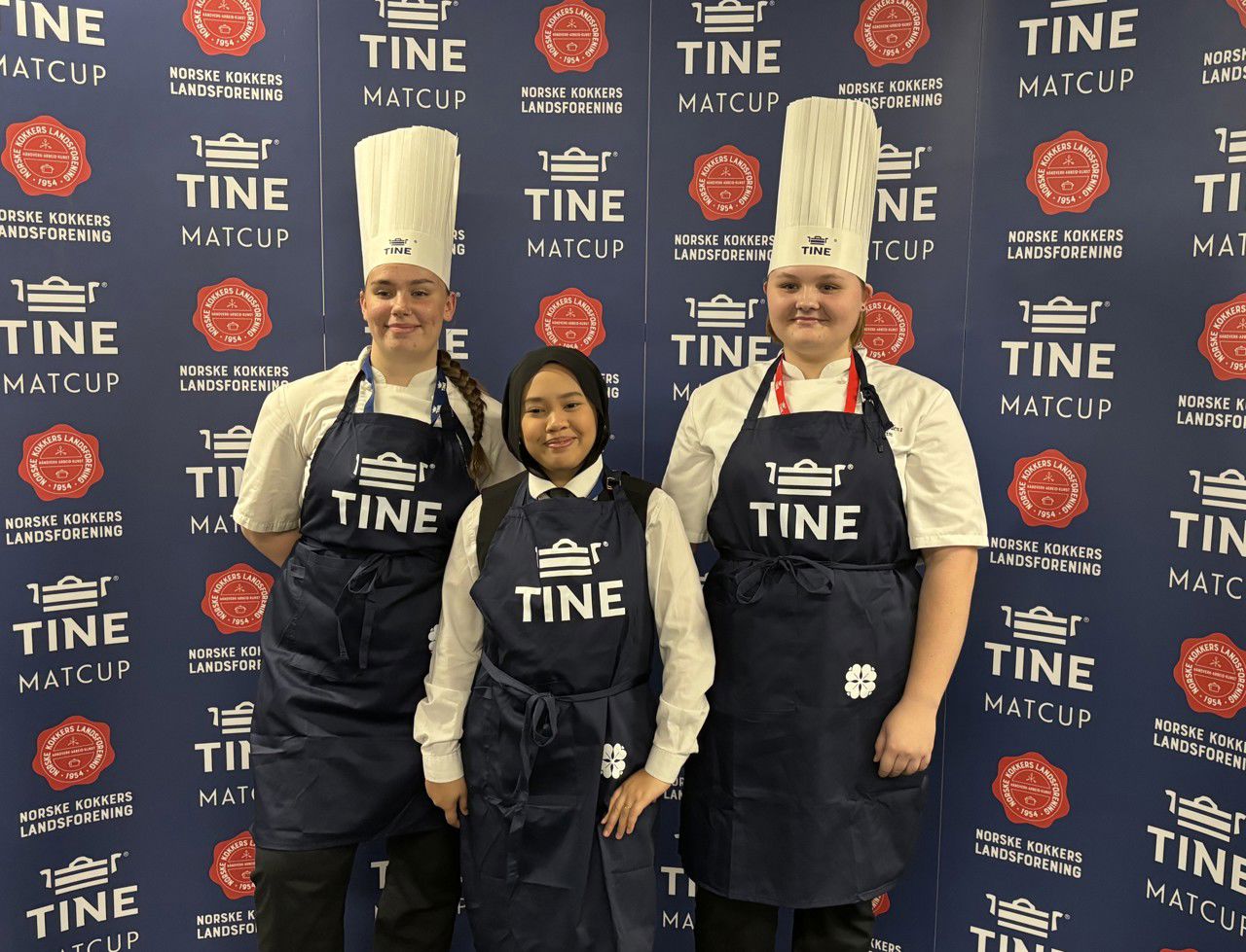 Tre jenter i kokkeuniform står framfor banner det det står Tine MatCup og norske kokkers landsforening