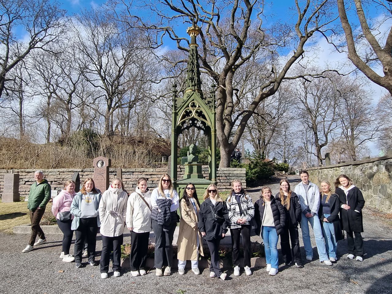 Ein skuleklasse som står framfor gravmonumentet for Henrik Wergeland