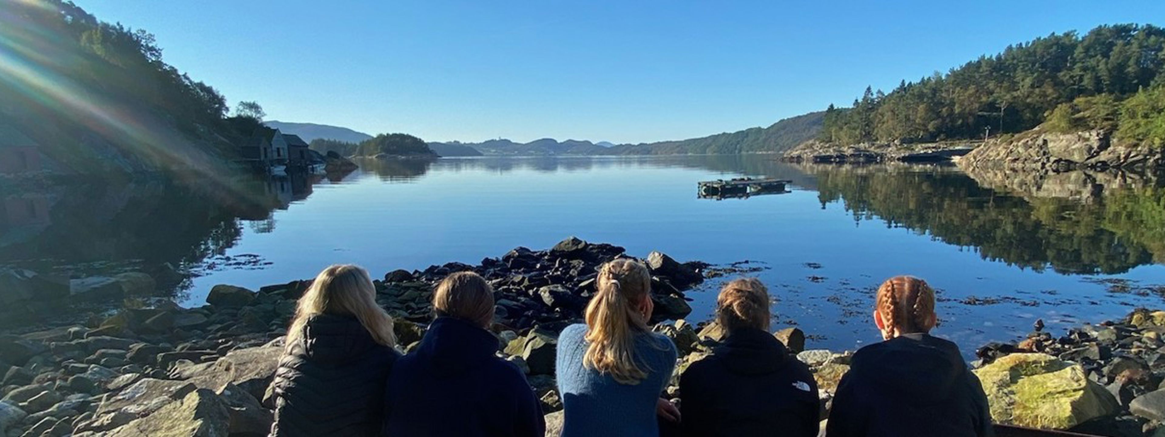 Elevar som sit med ryggen mot kamera og ser utover ein fjord