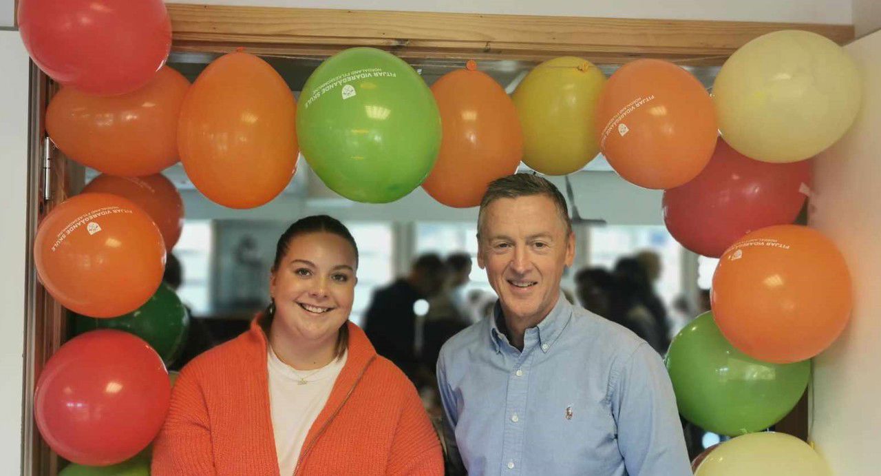 Ein elev og rektor som står i ein døropning med mange ballongar