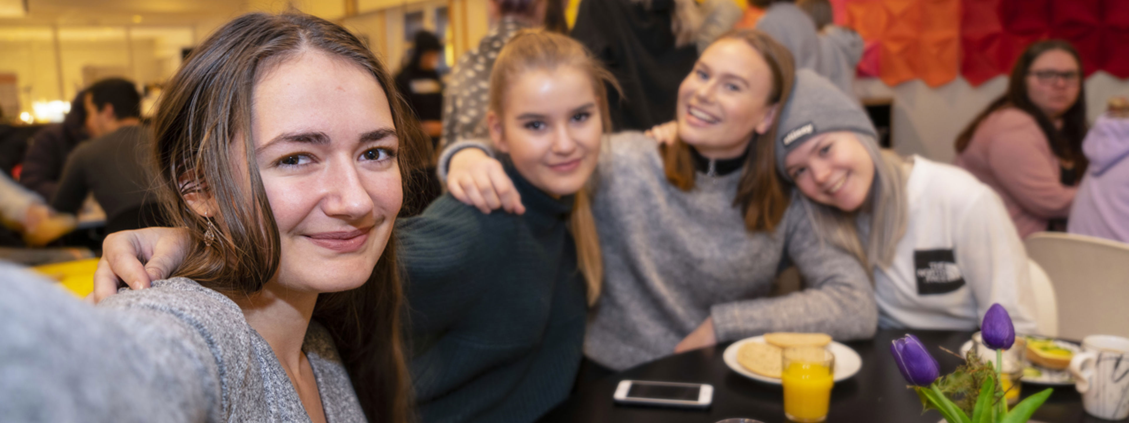 Elevar utanfor i kantina som smiler til kamera