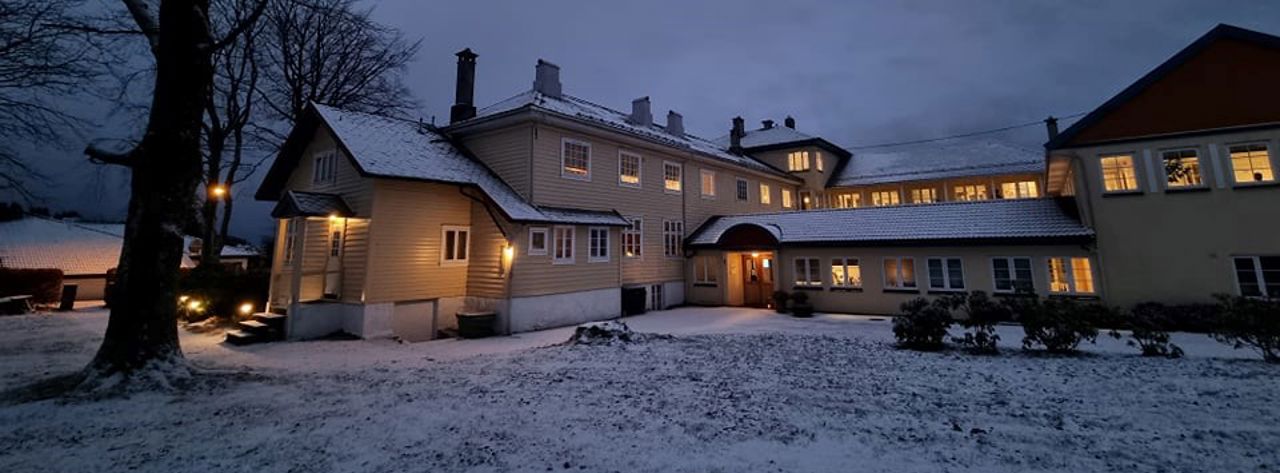 Gamledelen av skulen i blåtimen, ute er det vinter og snø