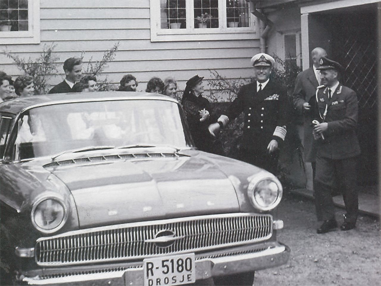 Svar kvitt bilete av Kong Olav V. som går ut av skulen og inn i ein bil