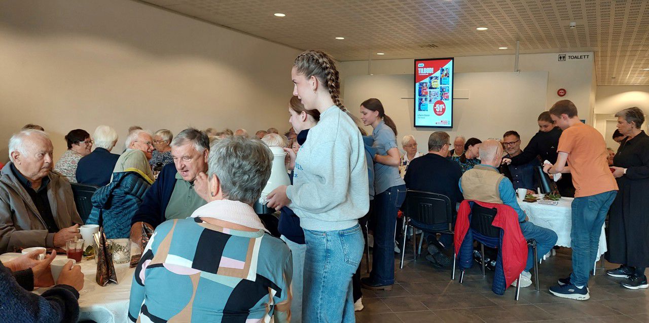 Elev som serverer seniorar som sit ved bordene