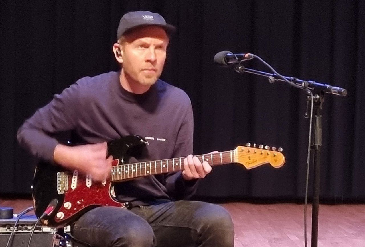 Ein gitarist sit og spelar på gitar